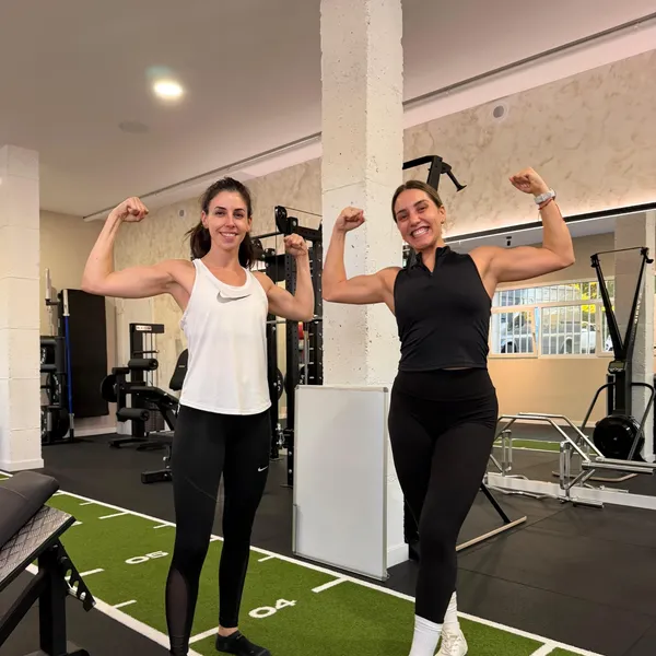 Dos clientas mostrando bíceps en la pista de césped